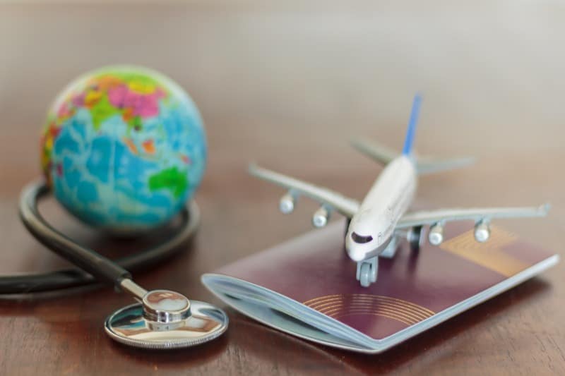 Photo qui montre un petit avion en plastique au-dessus d'un passeport à coté d'un petit globe terreste en plastique et un stratoscope